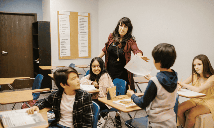 Una profesora reparte exámenes en su clase de Educación Primaria.