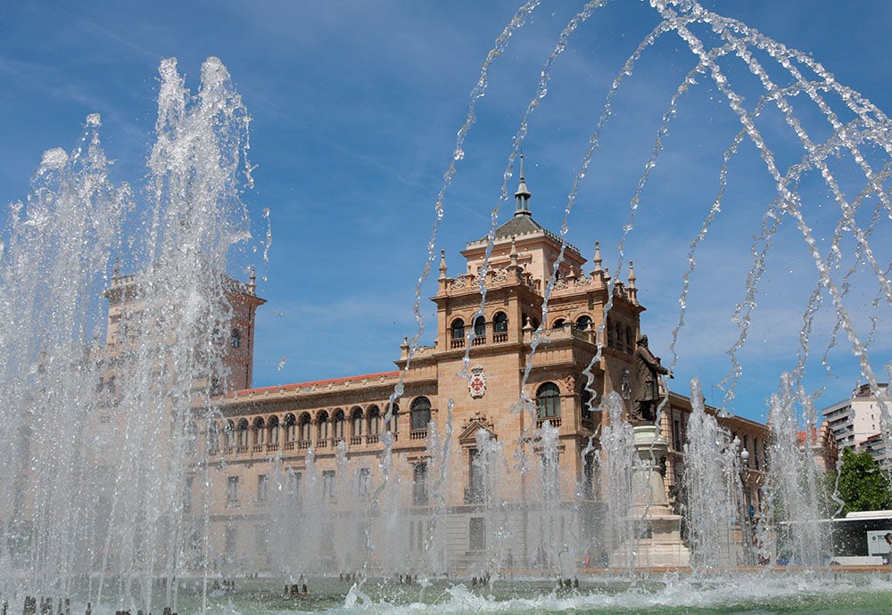 Imagen de la Academia de Caballería realizada detrás de la Fuente de Zorrilla, con el agua de la fuente en primer plano. 