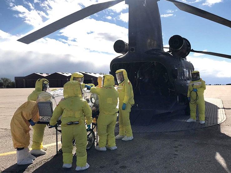 Sanitarios del Ejército evacuan a un herido en helicóptero ataviados con trajes para guerra bactereológica.