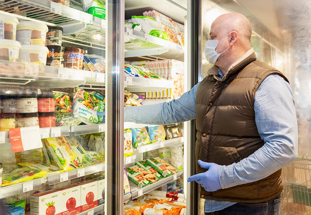 Cliente de supermercado en Moscú abre la nevera de la sección de refrigerados.