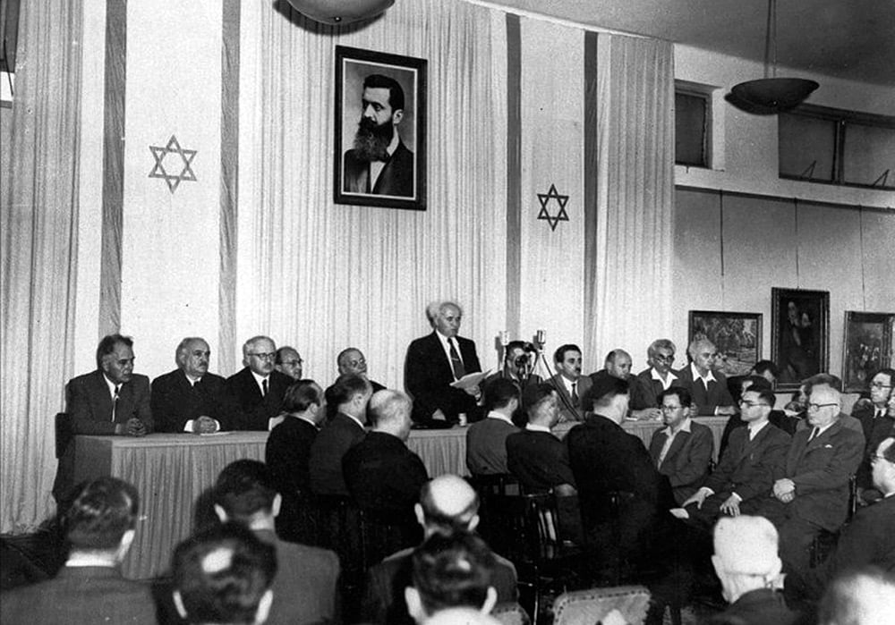 Ben Gurion lee la declaración de Independencia de Isarel, a las 4 de la tarde del 14 de mayo de 1948, en el Museo de Tel Aviv bajo el retrato de Herzl, el fundador del sionismo.