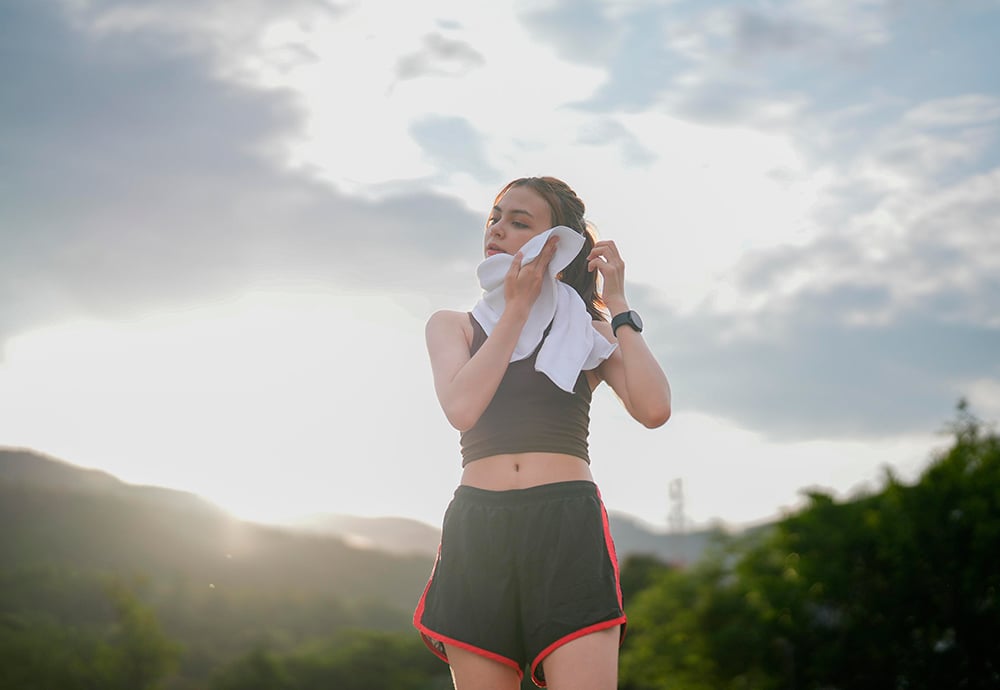 Una joven atleta se limpia el sudo con una toalla tras hacer deporte en un parque público