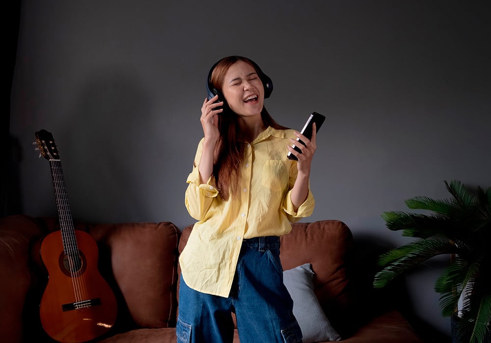 Una joven baila en el salón de su casa escuchando música desde el smartphone a través de sus auriculares 