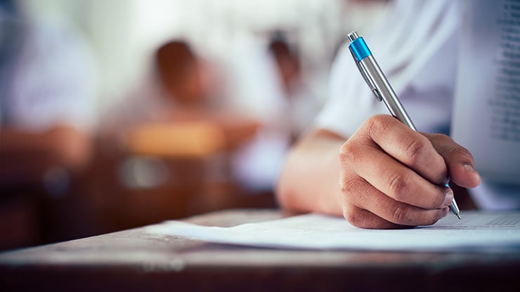 La mano de un estudiante sostiene un bolígrafo durante la realización de un examen.