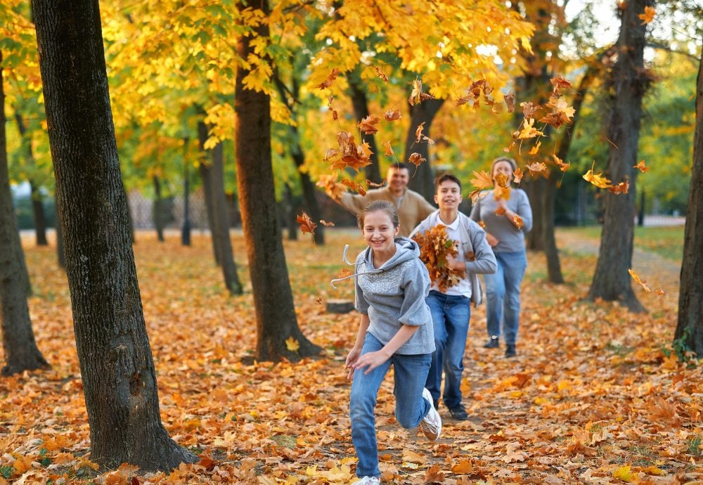 Familia corriendo por un bosque en otoño