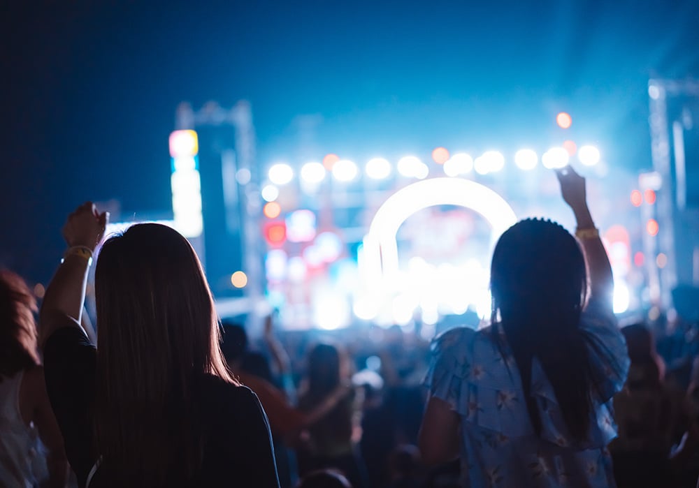Dos mujeres jóvenes disfrutan de un festival de música al aire libre.