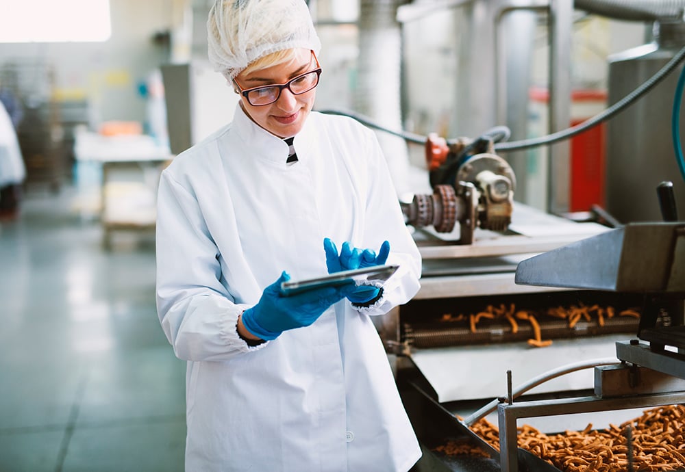 Una dietista-nutricionista realiza una evaluación de calidad en una fábrica de snacks.