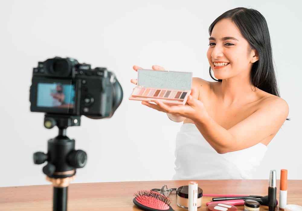 Influencer especializada en belleza muestra a la cámara un kit de maquillaje durante un directo.