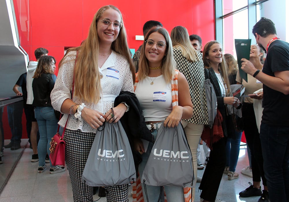 Dos nuevas estudiantes de la UEMC pasan para la cámara con sus nuevas mochilas grises de la universidad durante la Jornada de Bienvenida 2022.  