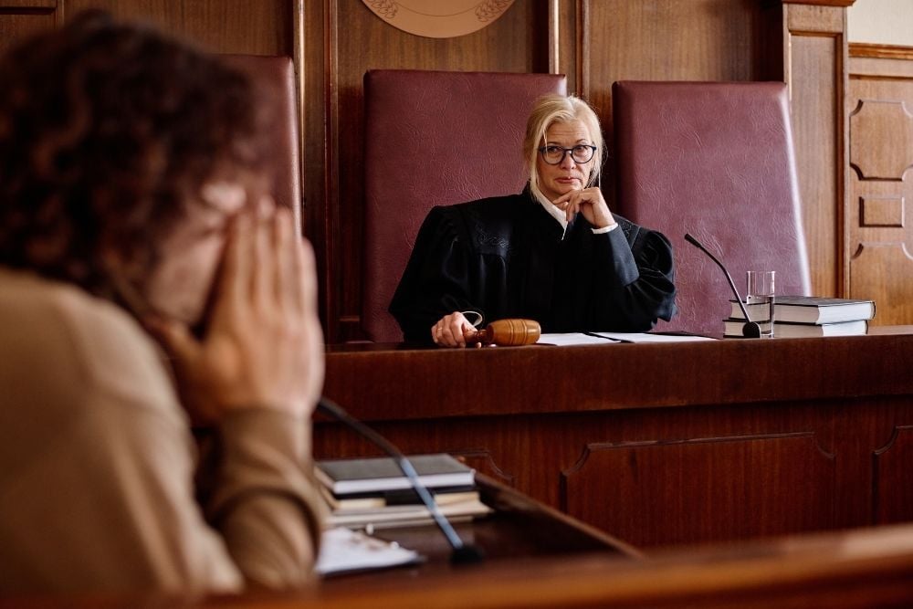 Vista de una sala de juicio con un juez en el estrado mientras una persona declara como testigo