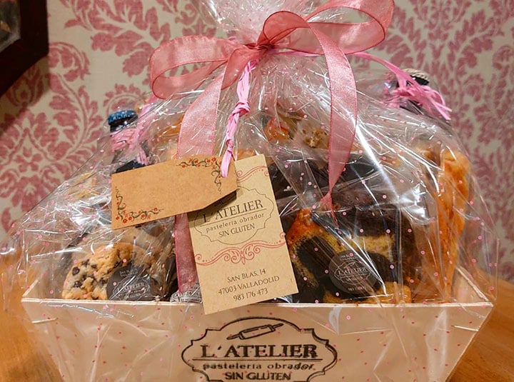 Una cesta con productos de la pastelería L'Atelier listo para regalos y en el que se indica que no llevan gluten.
