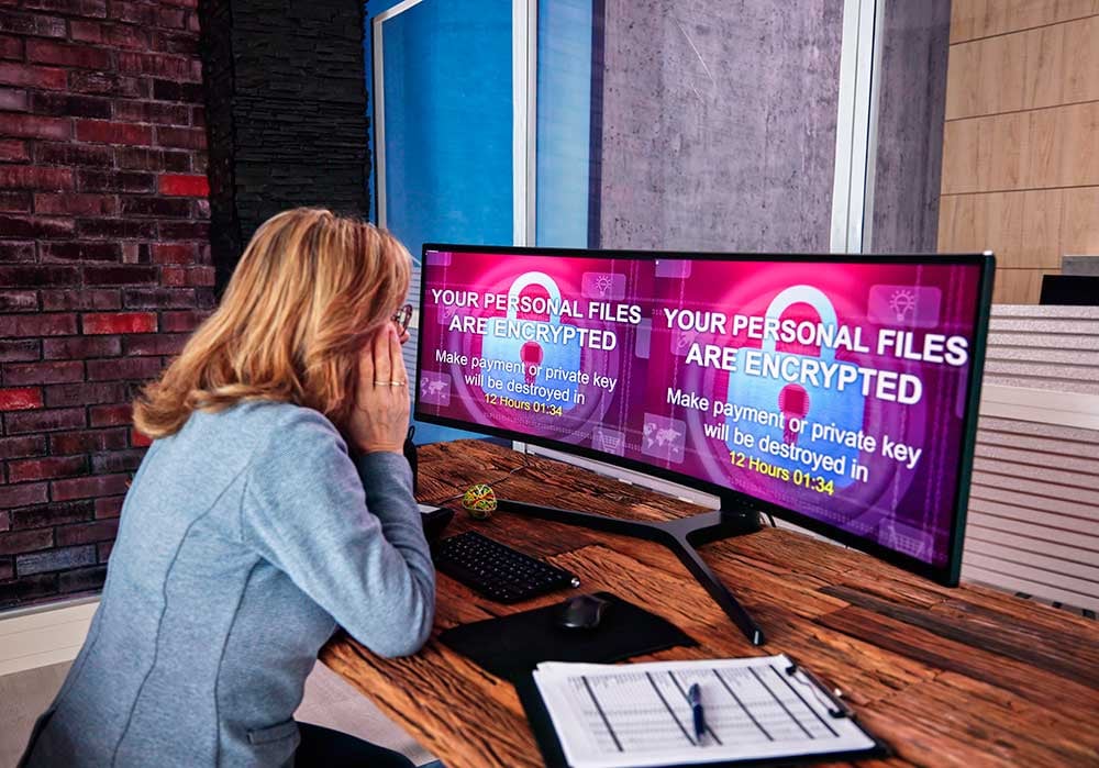 Una mujer está delante de unos ordenadores que en su pantalla muestran el mensaje de información encriptada.