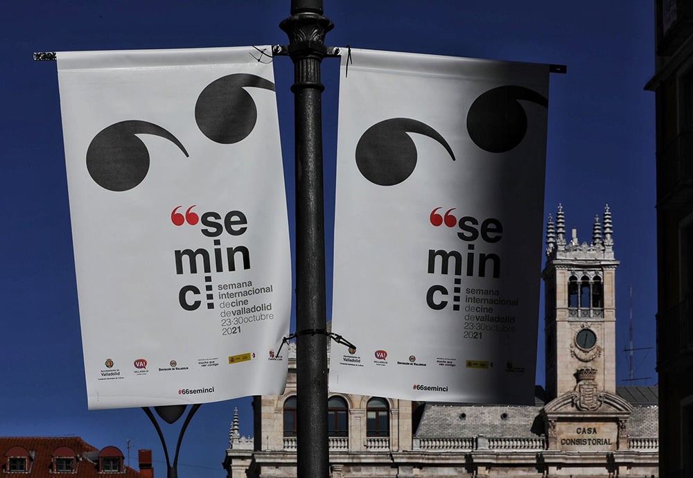 Dos banderolas con el cartel de la Seminci situadas en la calle Santiago de Valladolid con el ayuntamiento de fondo.