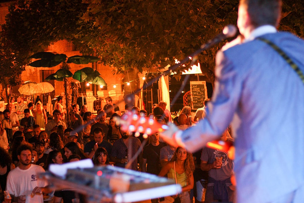 Un músico toca durante la noche en la Plaza Mayor de Simancas bajo la atenta mirada del público.