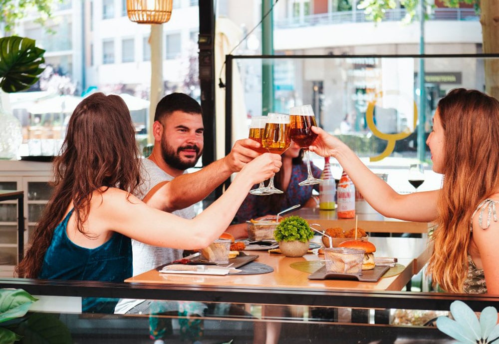 Un chico y dos chicas brindan con unas cervezas en la terraza del Periquete.