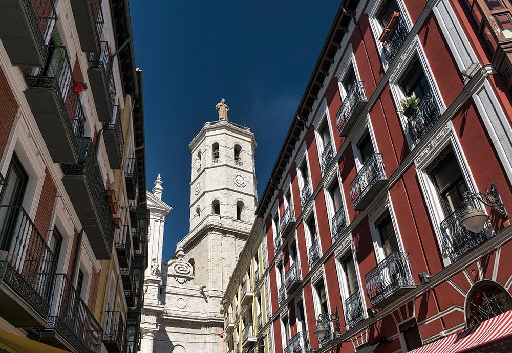 Torre de la catedral coronado con un Cristo sobresaliendo entre edificios del centro de Valladolid. 