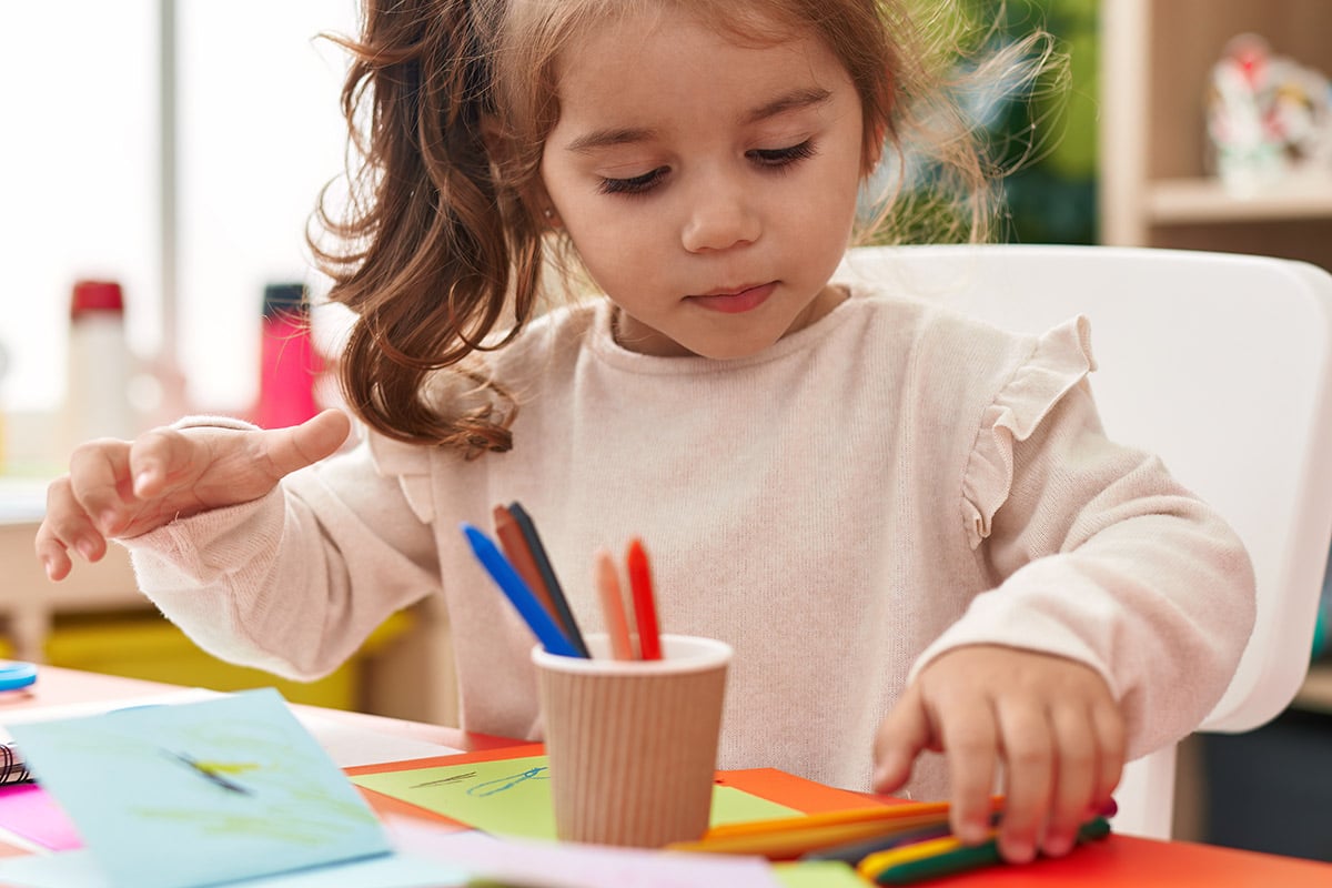 Niña pequeña haciendo una actividad con pinturas en clase. Niña pequeña haciendo una actividad con pinturas en clase.