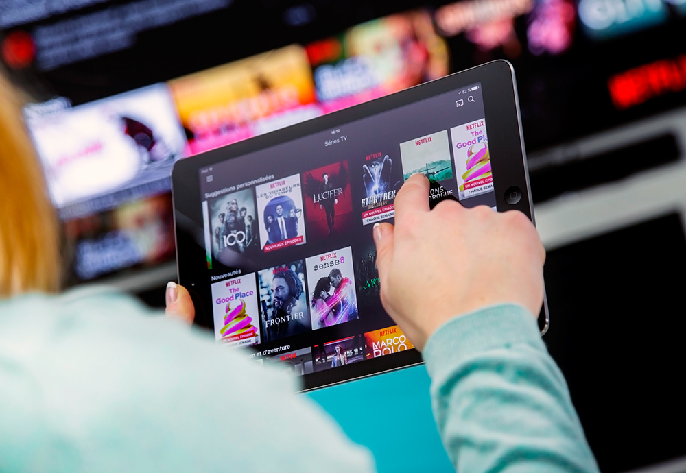 Una seóra busca una serie en versión original en Netflix a través de su tablet