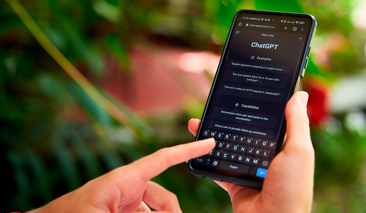 Dedo de una persona manipula un teléfono móvil en el que hay abierta la aplicación de ChatGPT.
