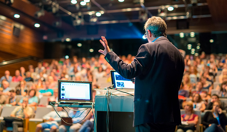 Un hombre realiza una buena presentación en público ante un auditorio lleno.