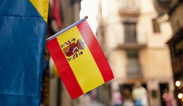 Una pequeña bandera española decora la fachada de una calle del casco viejo de una ciudad.