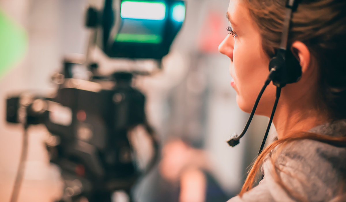 Estudiante operando una cámara de televisión en un plató durante prácticas del Grado en Comunicación Audiovisual