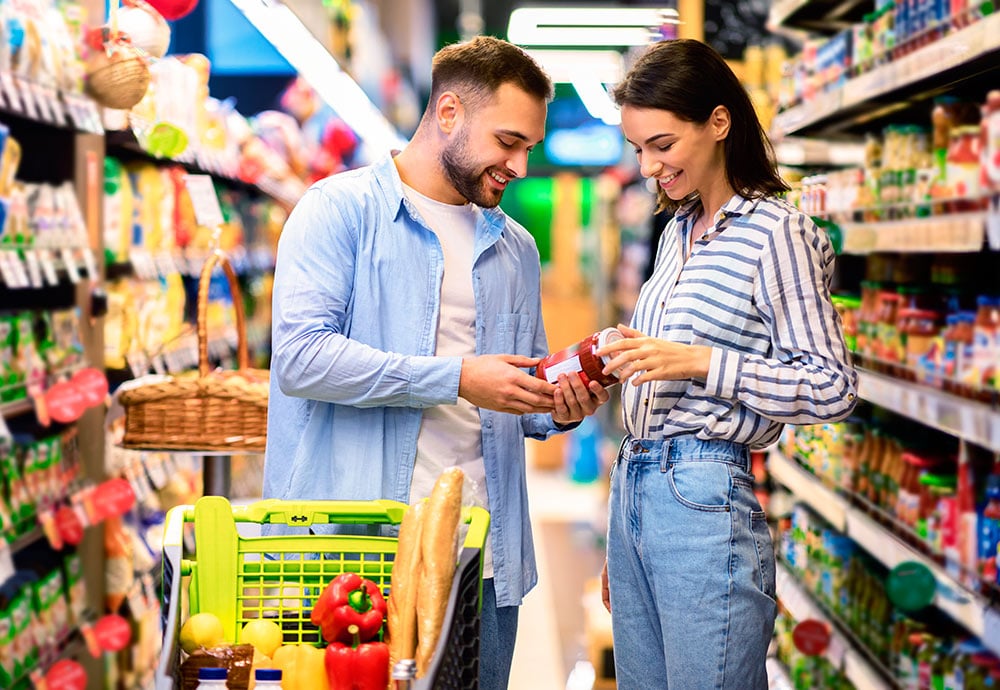 Una pareja en un supermercado comparan un producto envasado
