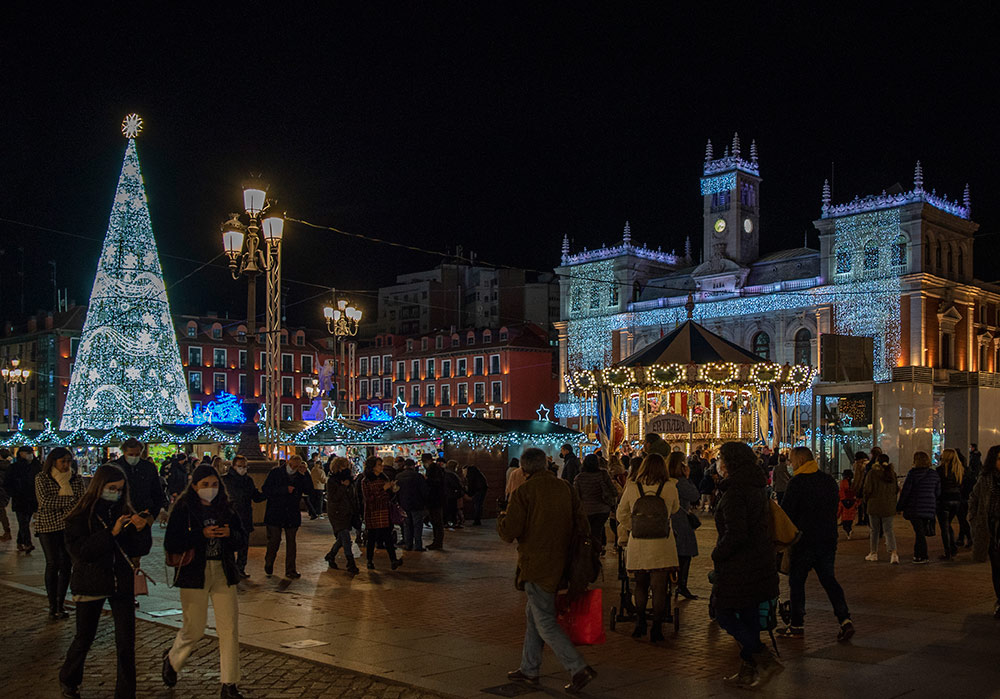 Gente paseando por la Plaza Mayor de Valladolid y que luce su estampa navideña con las luces, el mercado navideño o el Árbol de los Deseos.