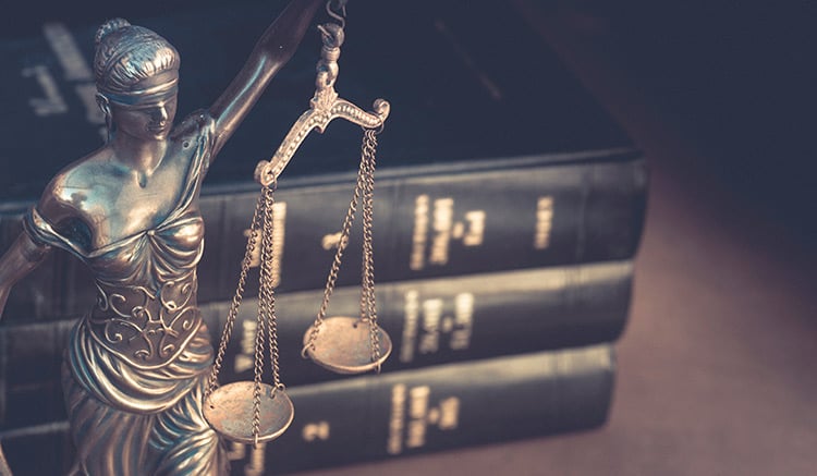 Figura que representa a la Justicia delante de tres manuales de Derecho.