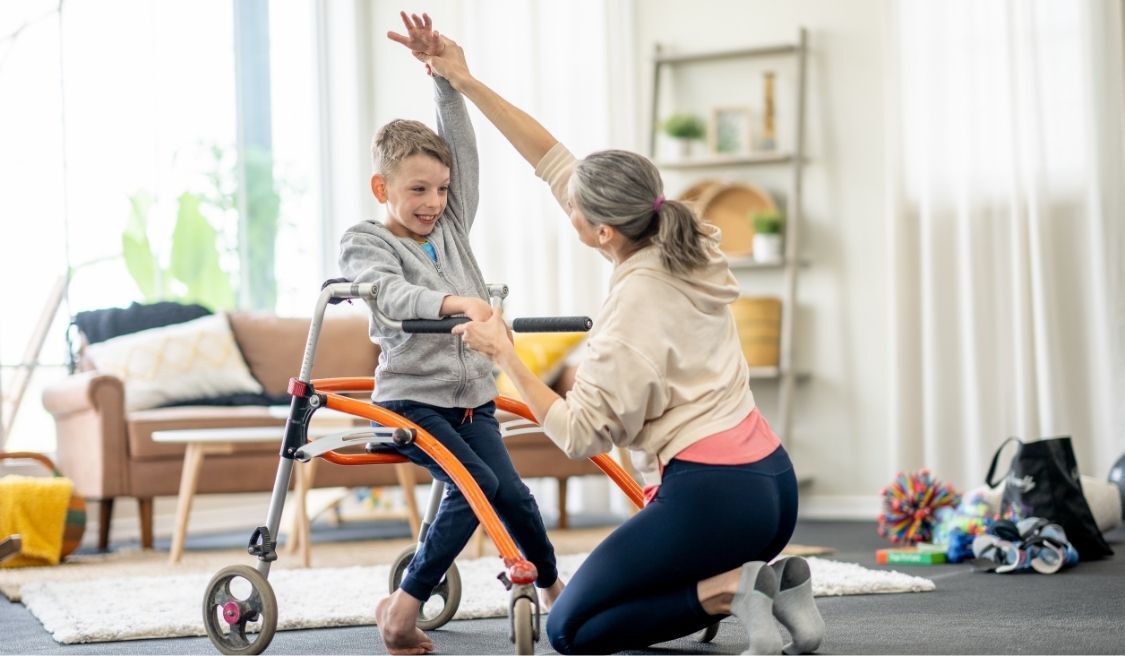 Sesión de terapia ocupacional infantil centrada en la rehabilitación de la movilidad con apoyo profesional y uso de un andador en un entorno doméstico