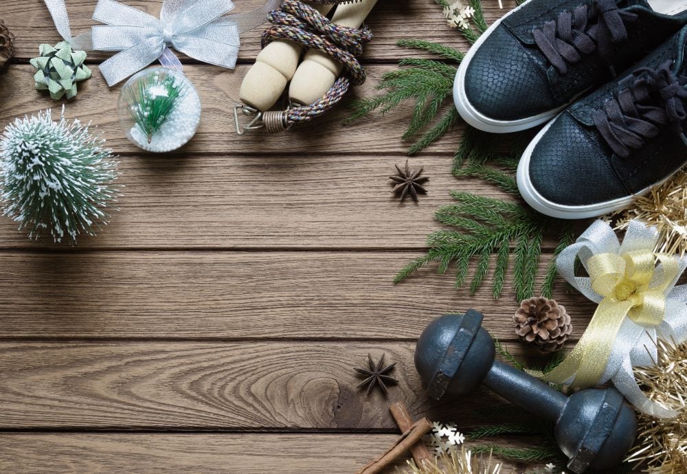 Detalle de unas zapatillas, una mancuerna y distintos adornos navideños sobre unos tablones de madera.