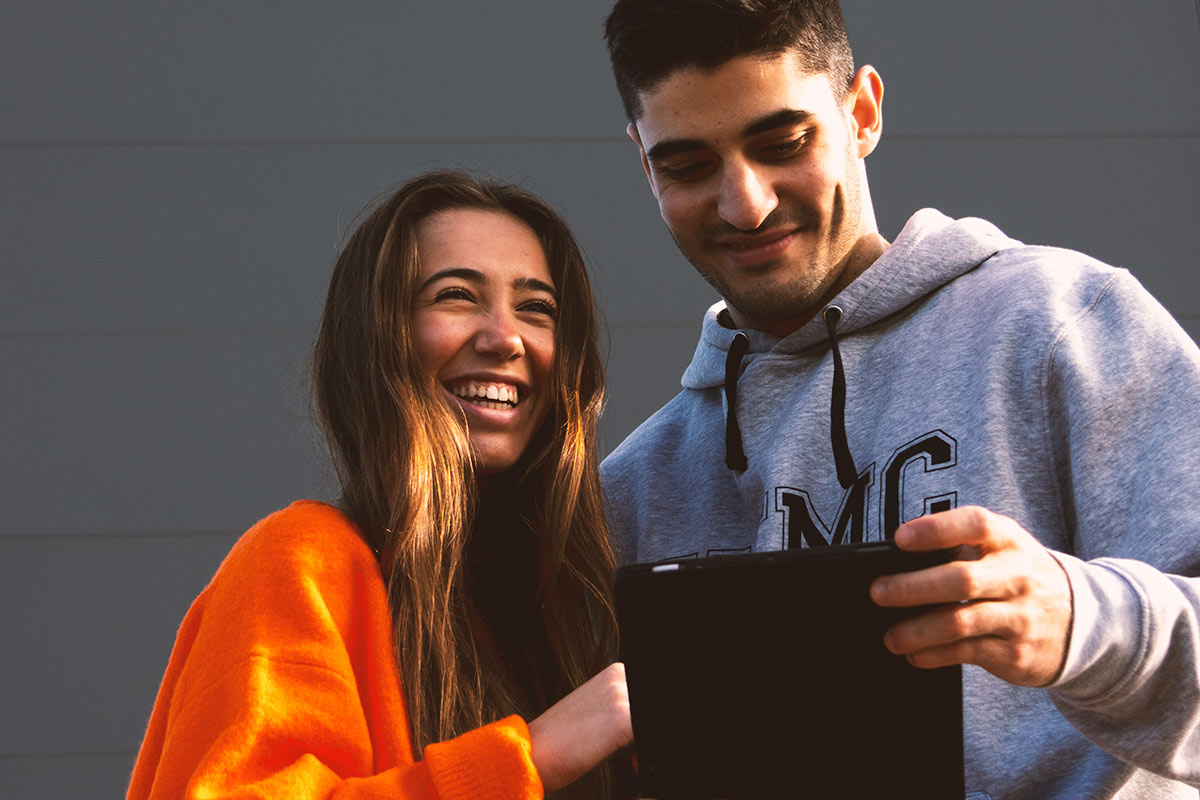 Un chico y una chica mirando una tablet. Uno de ellos viste una sudadera de la UEMC.